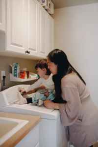 Mother helping child operate a washing machine